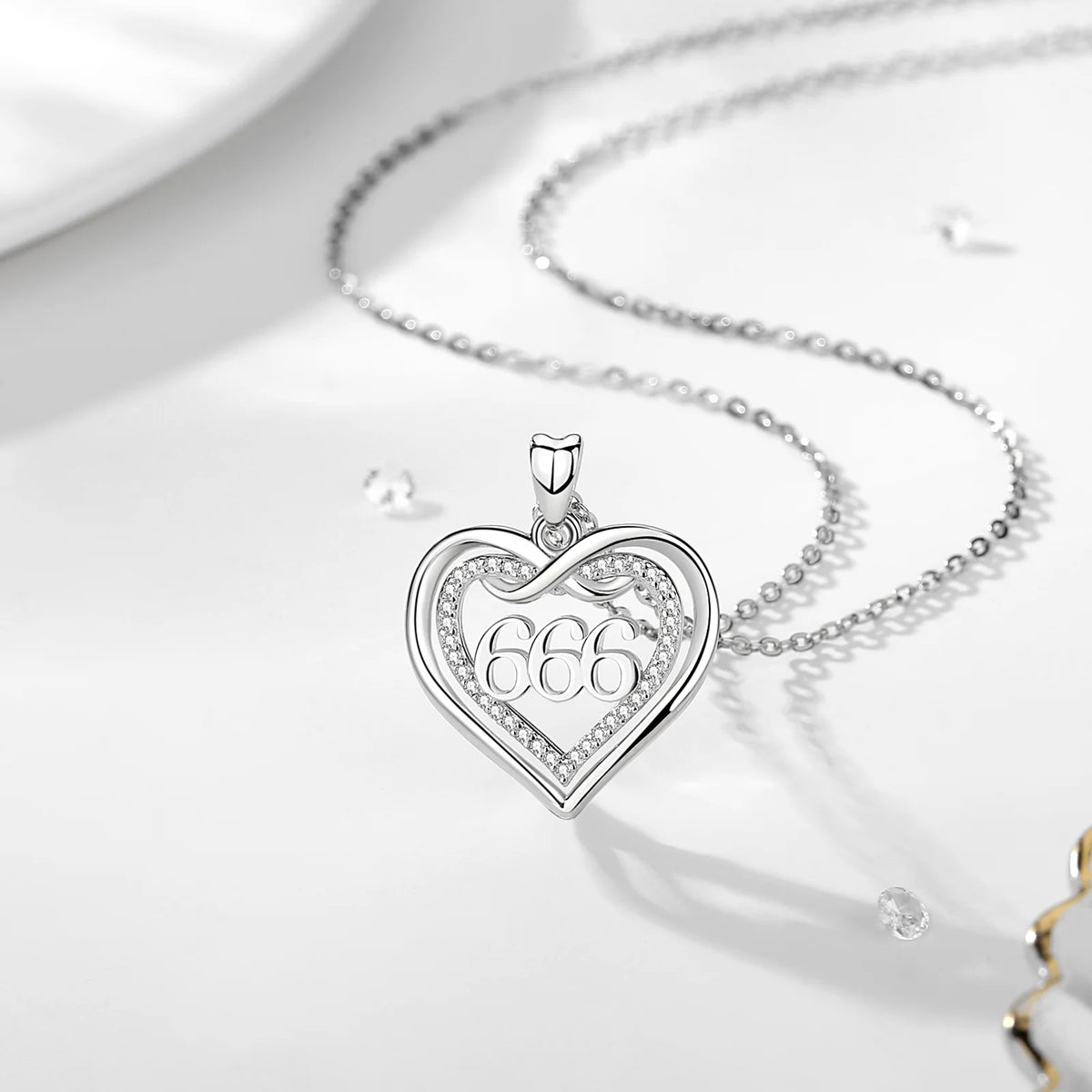666 silver infinity heart pendant suspended from a fine chain on a white surface