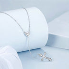 Side view of the silver cross lariat with its stone-set heart connector and pointed CZ cross