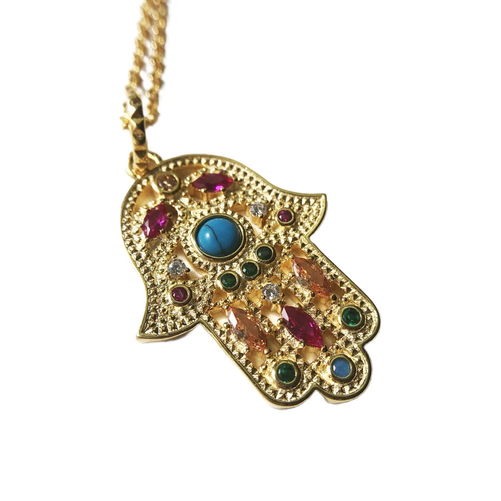 Angled close-up of the vintage hamsa pendant with a turquoise-colored center and multicolor stones on a white background