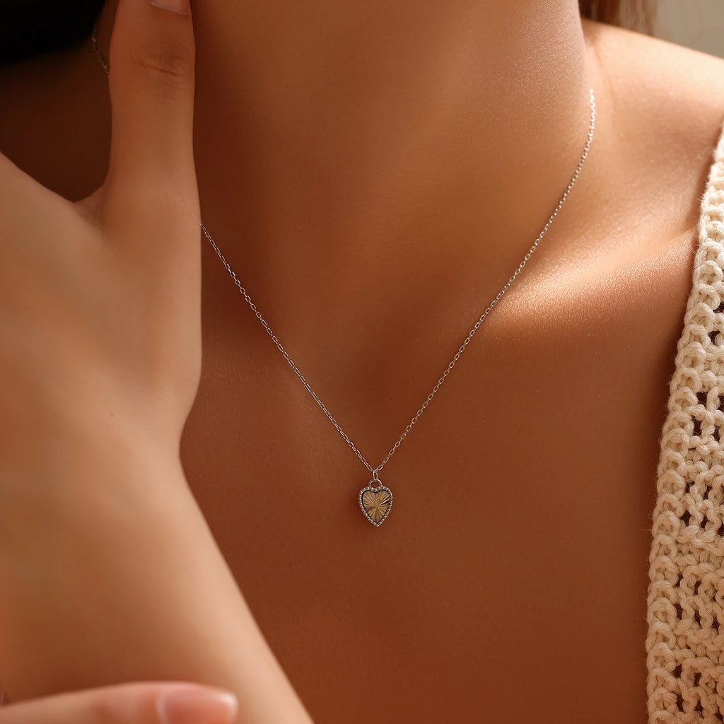 925 sterling silver heart necklace worn with a knit top, showing the beaded edge and radiating center