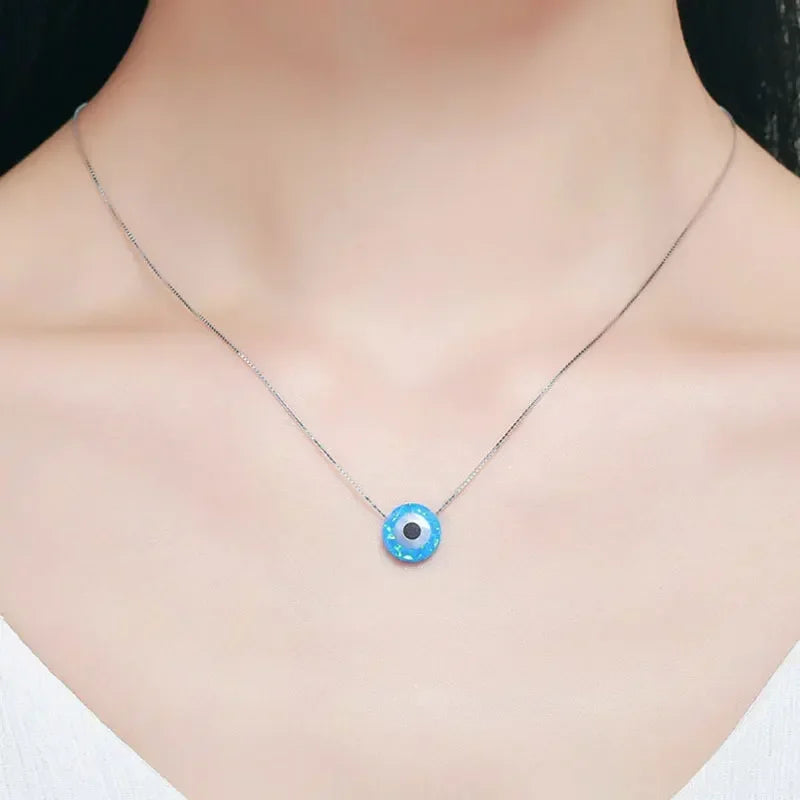 Blue synthetic opal evil eye necklace worn at the base of the neck on a fine silver chain