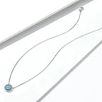 Blue evil eye necklace laid out on a white surface with clasp and extender visible