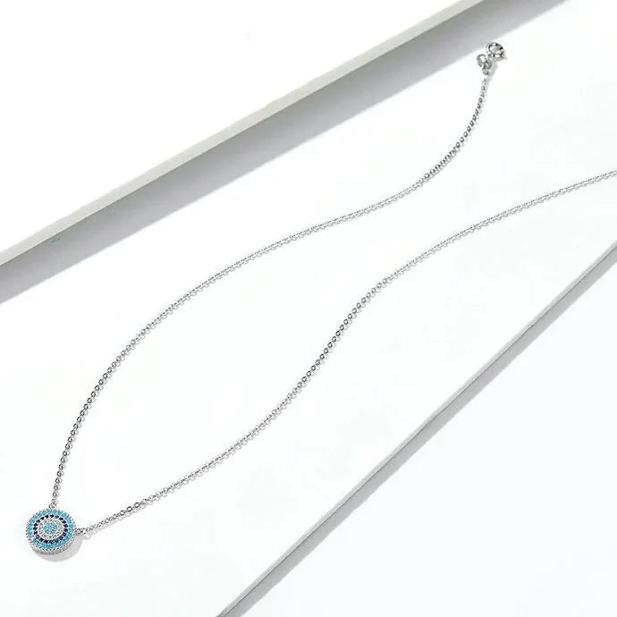 Blue evil eye necklace laid out on a white surface with clasp and extender visible