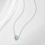 Fine oval-link chain necklace with a light blue heart and multicolored stone laid on a white surface