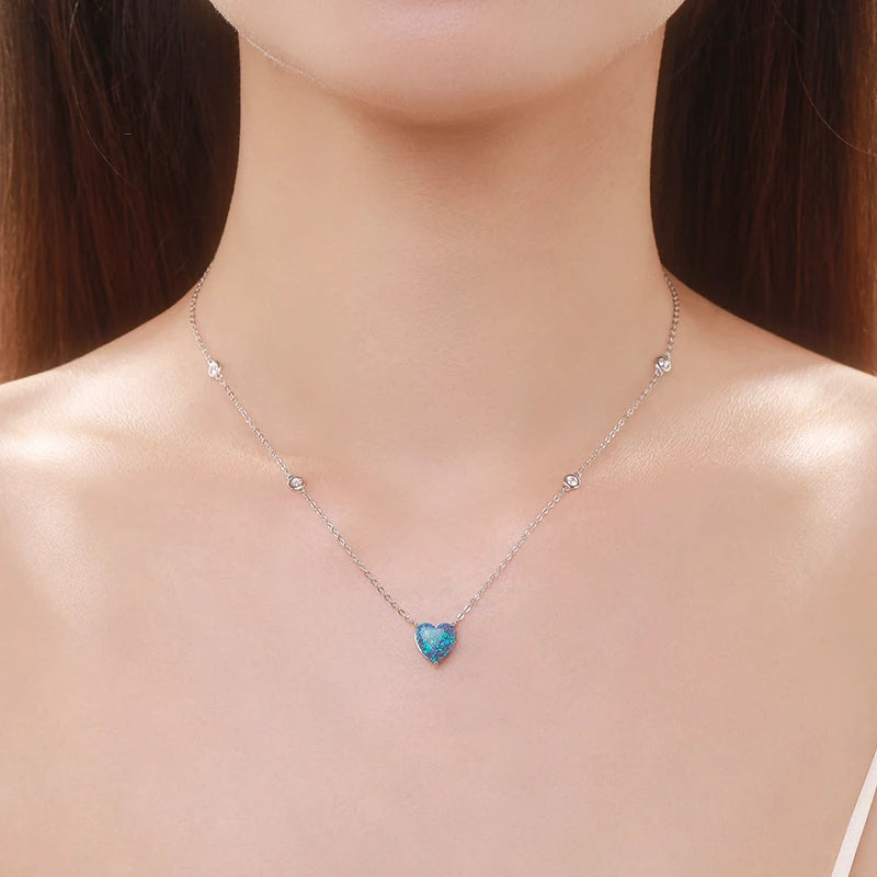 Silver-tone blue heart necklace worn at the collarbone with two clear crystals along the chain