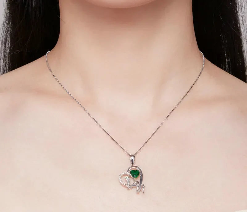 Snake and green heart necklace worn at the collarbone, showing the small pendant scale