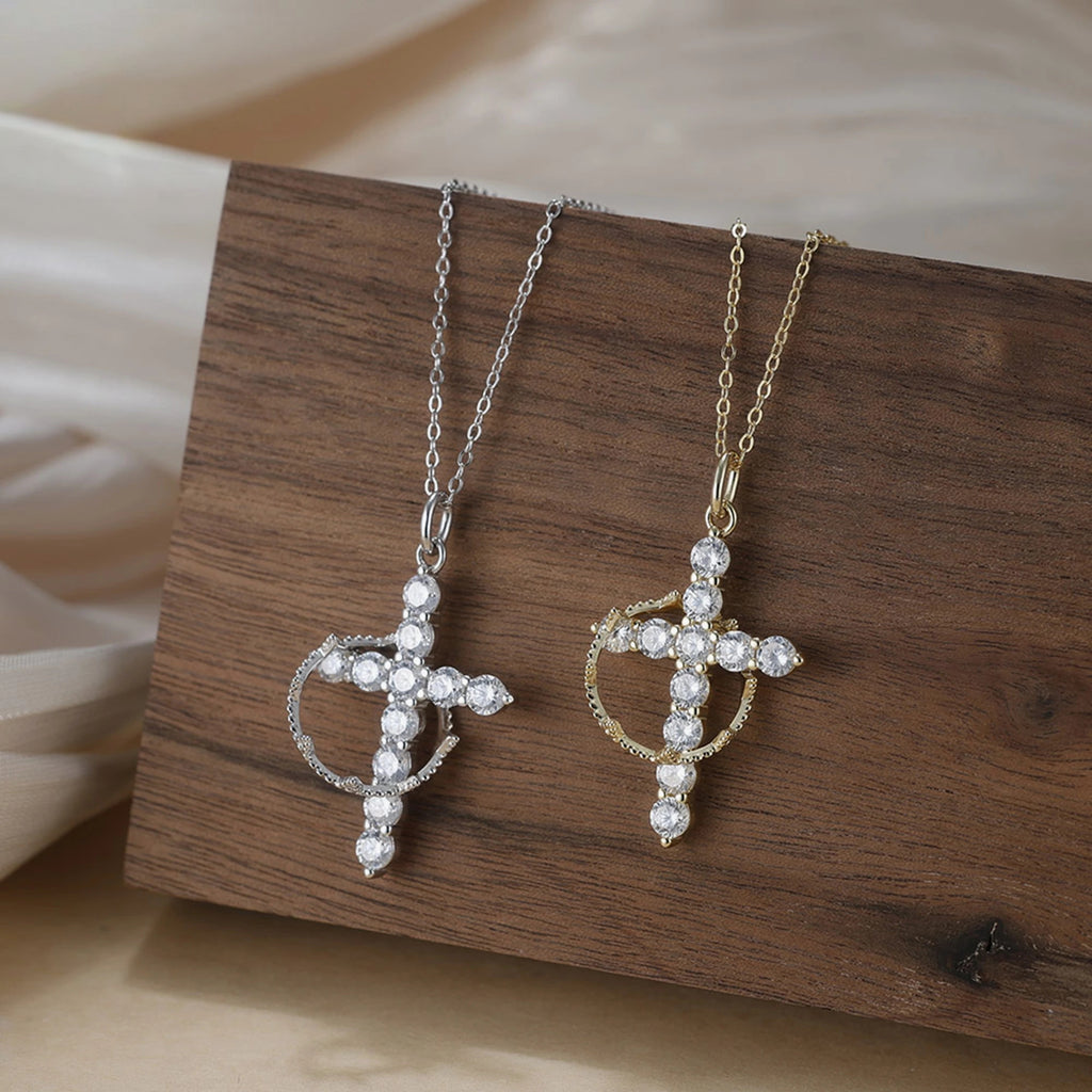 Crown of thorns cross necklaces in silver-tone and gold-tone, displayed on a wooden block