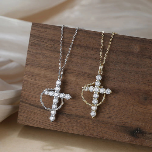 Crown of thorns cross necklaces in silver-tone and gold-tone, displayed on a wooden block