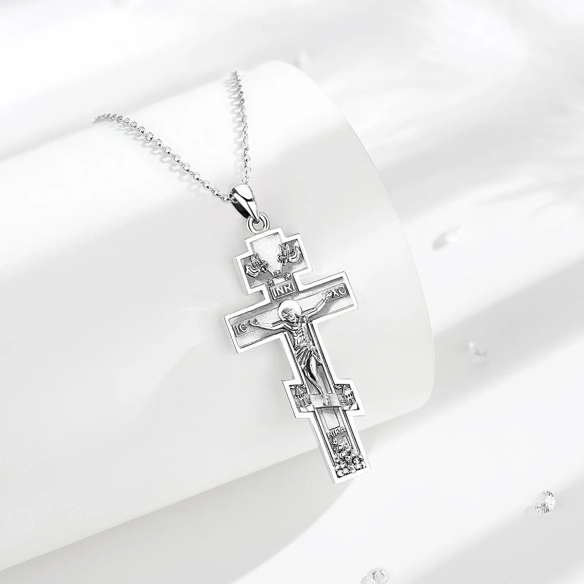 925 sterling silver crucifix necklace displayed on white curved props with textured cross details