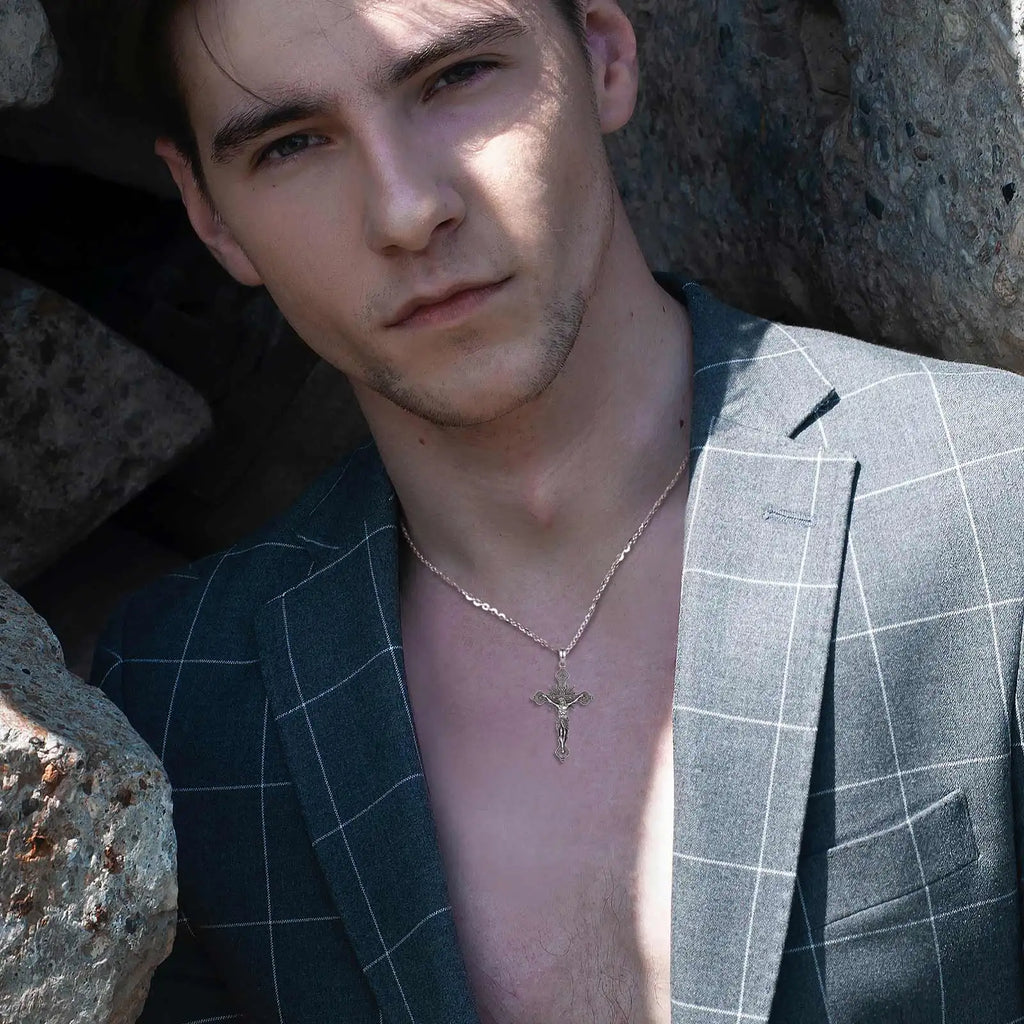 Detailed crucifix necklace worn with an open jacket, showing the silver cross at the chest