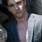Detailed crucifix necklace worn with an open jacket, showing the silver cross at the chest
