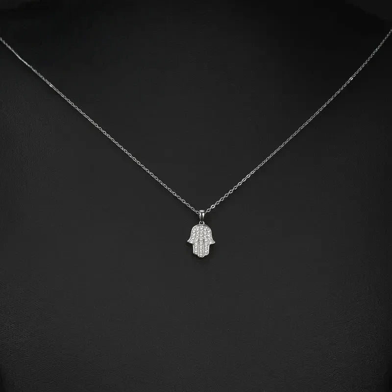 Fine oval-link necklace with a small clear CZ Hamsa pendant displayed against a black background