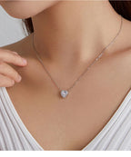 Clear CZ heart pendant on a fine chain worn above a white V-neck top