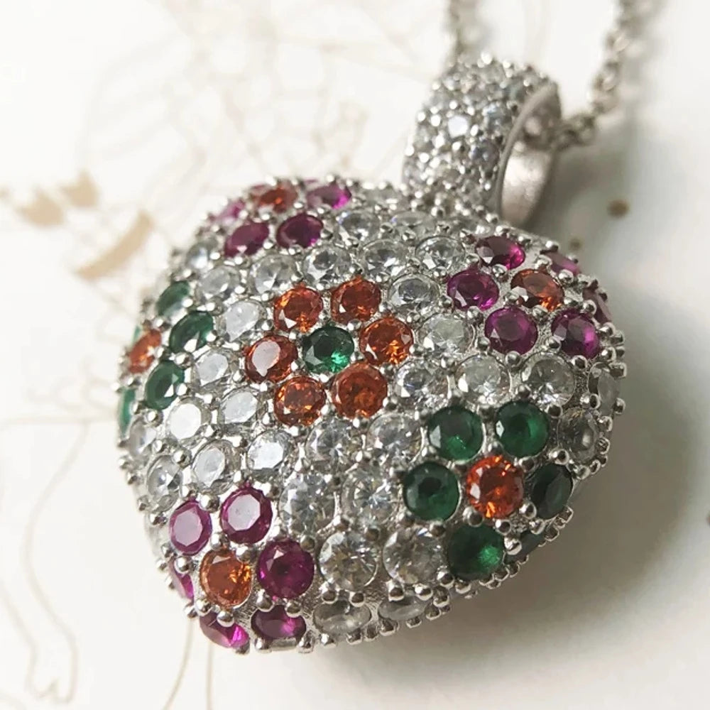 Angled close-up of the domed heart pendant with clear CZ stones and pink, green, and orange flowers
