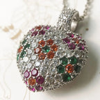 Angled close-up of the domed heart pendant with clear CZ stones and pink, green, and orange flowers