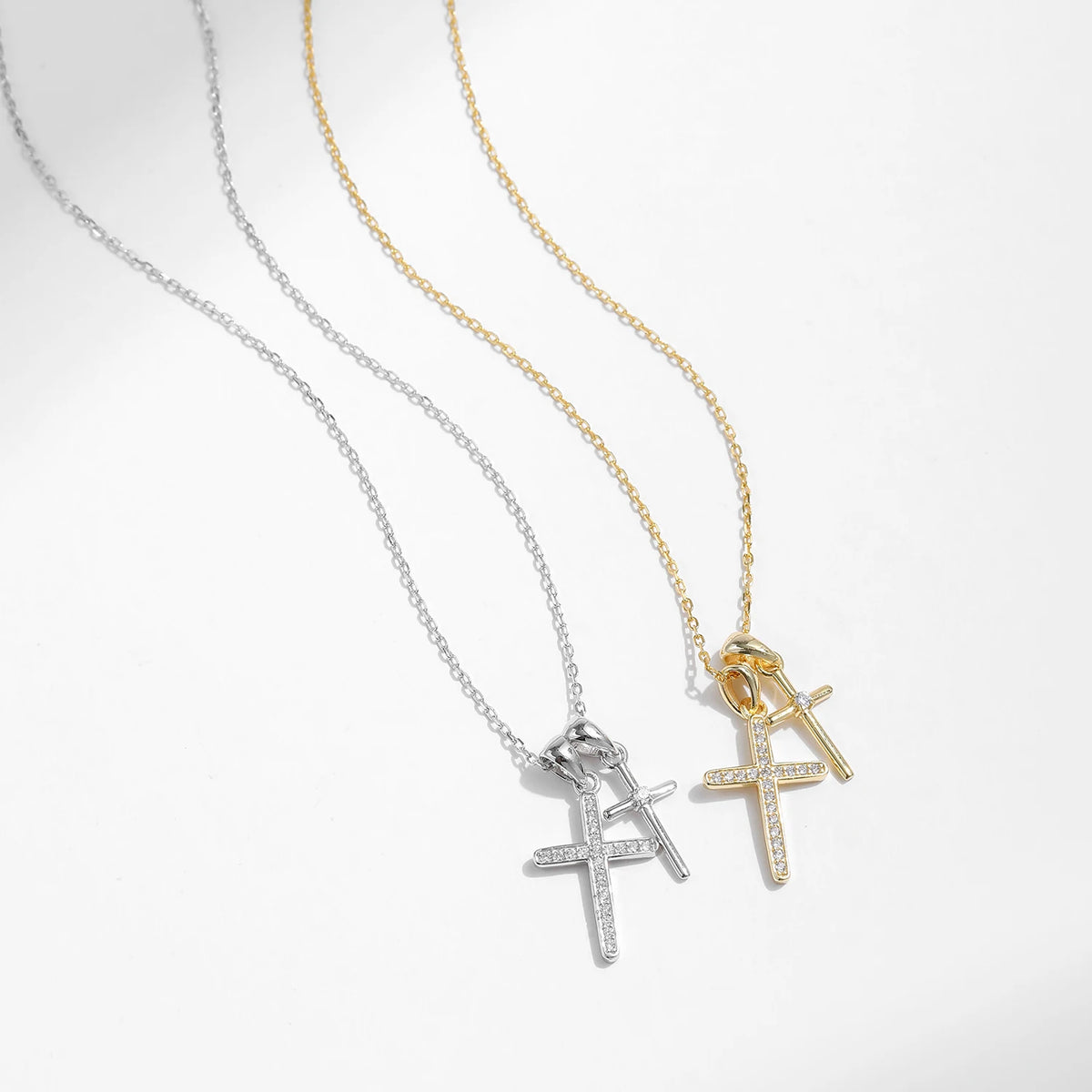 Two double cross necklaces in silver-tone and gold-tone arranged on a white background