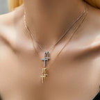 Silver-tone and gold-tone double cross necklaces worn layered at the base of the neck