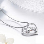 Back view of the sterling silver double-heart pendant and box chain on a white surface