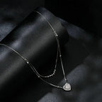 Sterling silver double-strand heart necklace displayed on black satin with a moissanite center stone