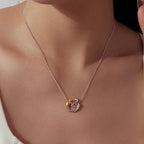 Gold-plated and white-gold-plated embracing figures necklace worn on a model's neck