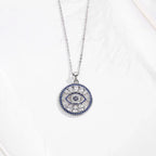 Round evil eye pendant necklace displayed flat with clear and blue cubic zirconia stone details