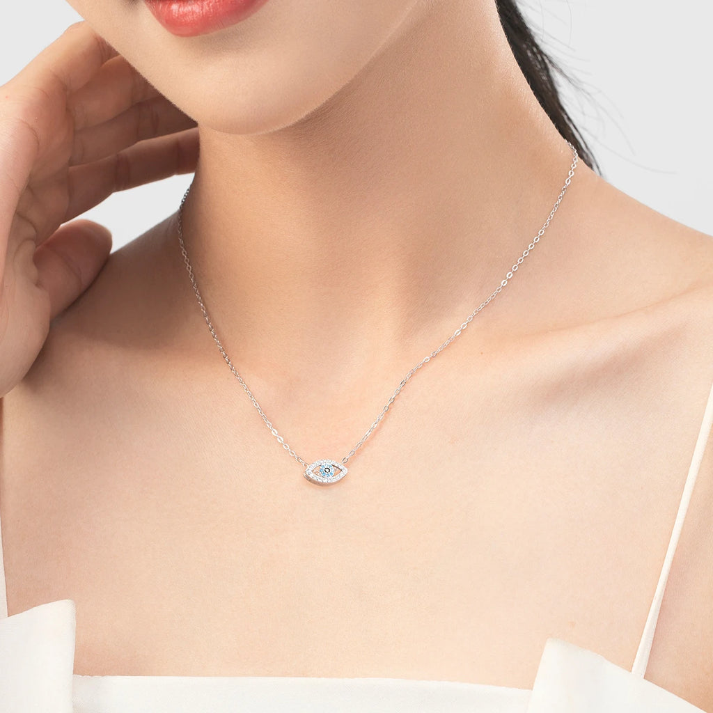 Silver-tone evil eye necklace worn at the collarbone with a blue and black stone center