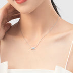 Silver-tone evil eye necklace worn at the collarbone with a blue and black stone center