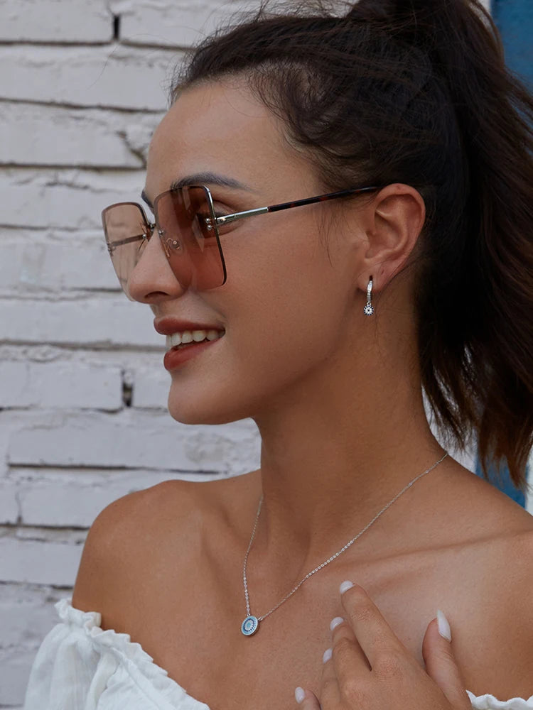 Round blue evil eye necklace worn at the collarbone with a silver-colored chain