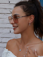 Round blue evil eye necklace worn at the collarbone with a silver-colored chain