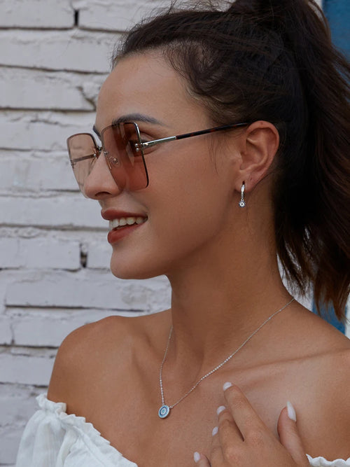 Round blue evil eye necklace worn at the collarbone with a silver-colored chain