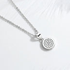 Back view of the round silver-tone evil eye pendant showing perforations behind the stone settings