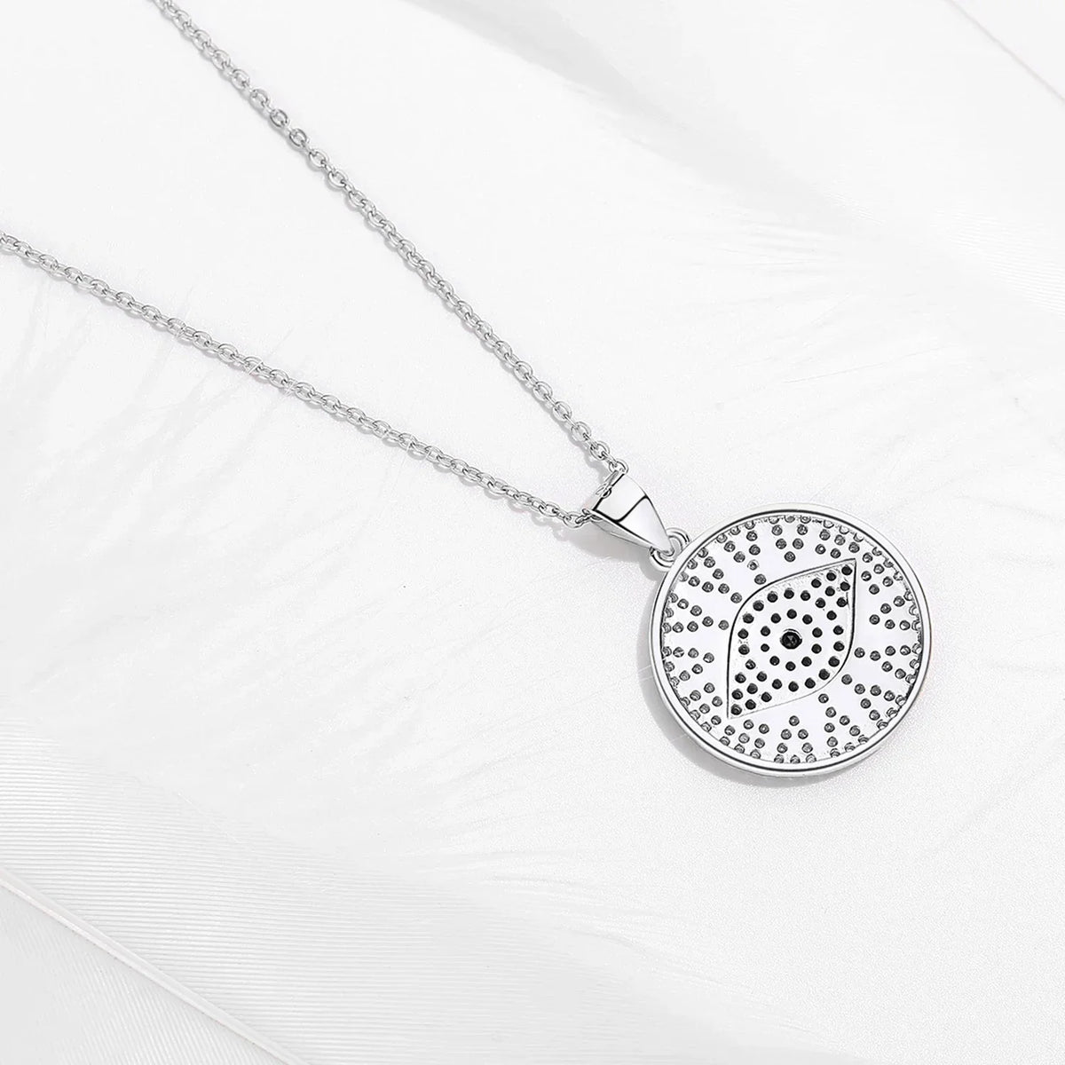 Back view of the silver-tone round evil eye pendant with open perforations behind the stones