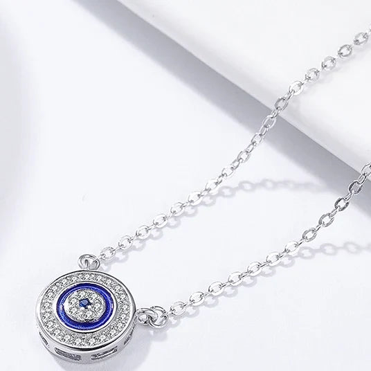 Close-up flat lay of the round blue evil eye pendant with side loops and a clear cubic zirconia border