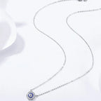 Full-length 925 sterling silver necklace arranged on a white surface with the small blue evil eye pendant