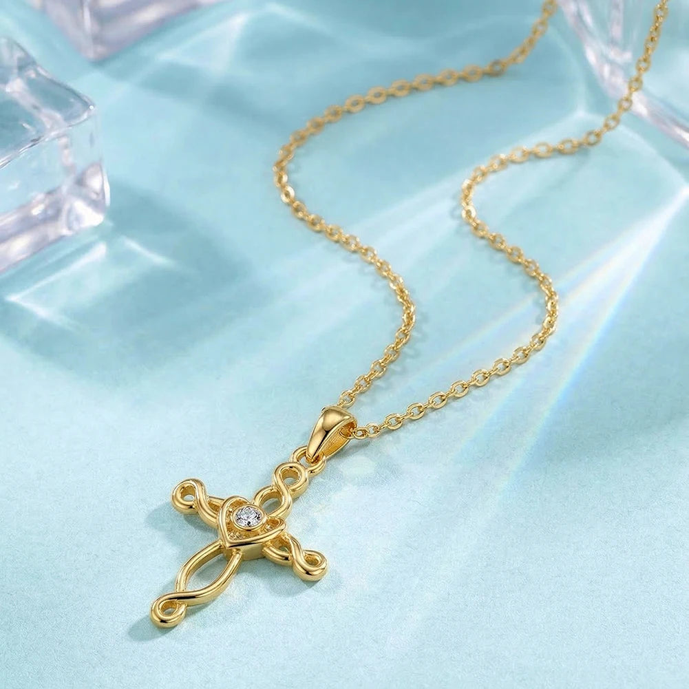 Gold-tone Celtic cross necklace arranged on pale blue fabric with an open heart center