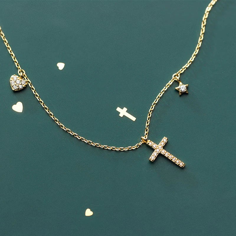Gold-tone fine link necklace with a sparkling cross, heart charm, and tiny star