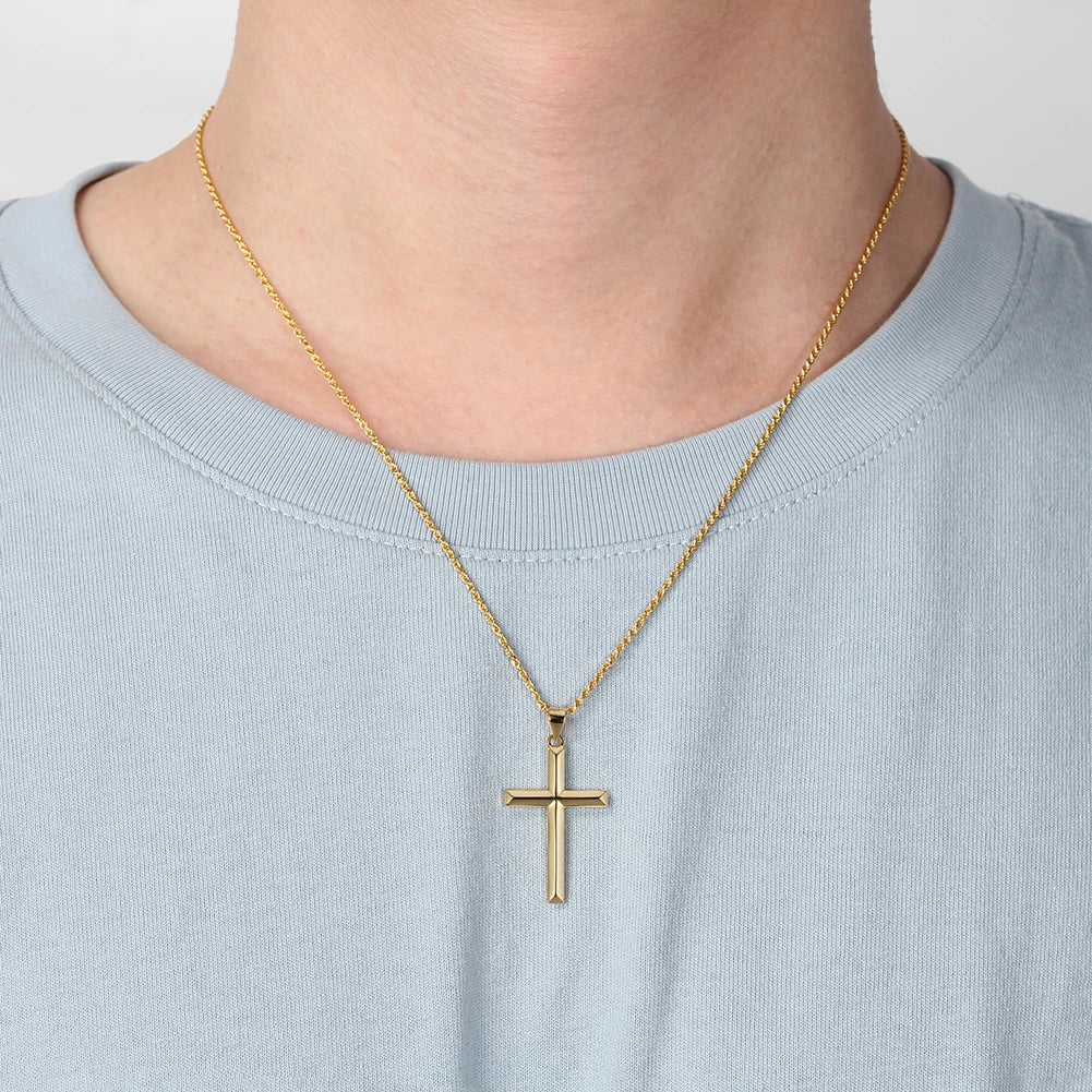 Gold-tone pointed cross necklace centered over a pale blue crewneck shirt