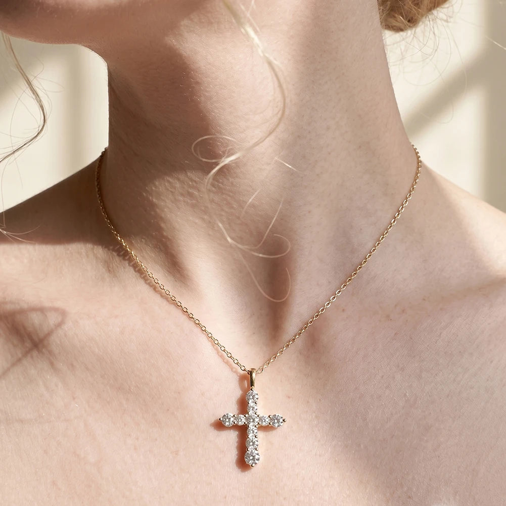 Gold-tone cross necklace with clear round stones worn at the base of the throat