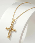 Gold-tone Celtic cross pendant displayed on a curved white stand with oval-link chain and heart center