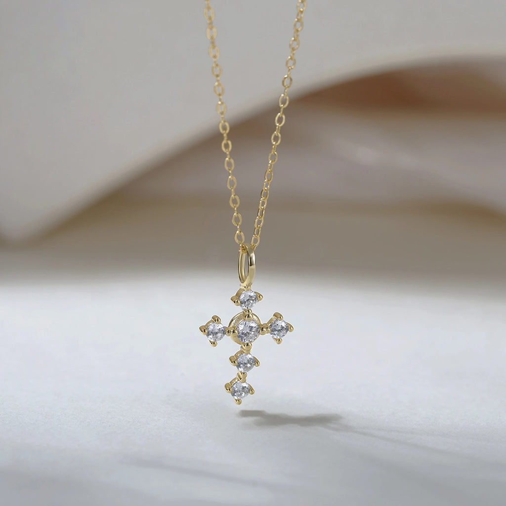 Gold-tone cross necklace with six clear cubic zirconia stones and an elongated bail