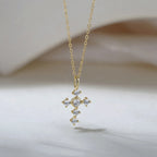 Gold-tone cross necklace with six clear cubic zirconia stones and an elongated bail
