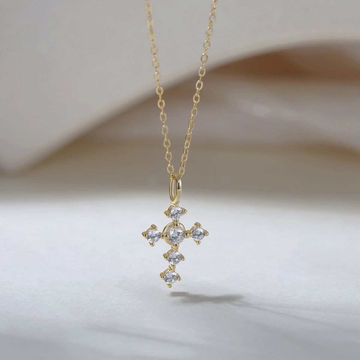 Gold-tone cross necklace with six clear cubic zirconia stones and an elongated bail