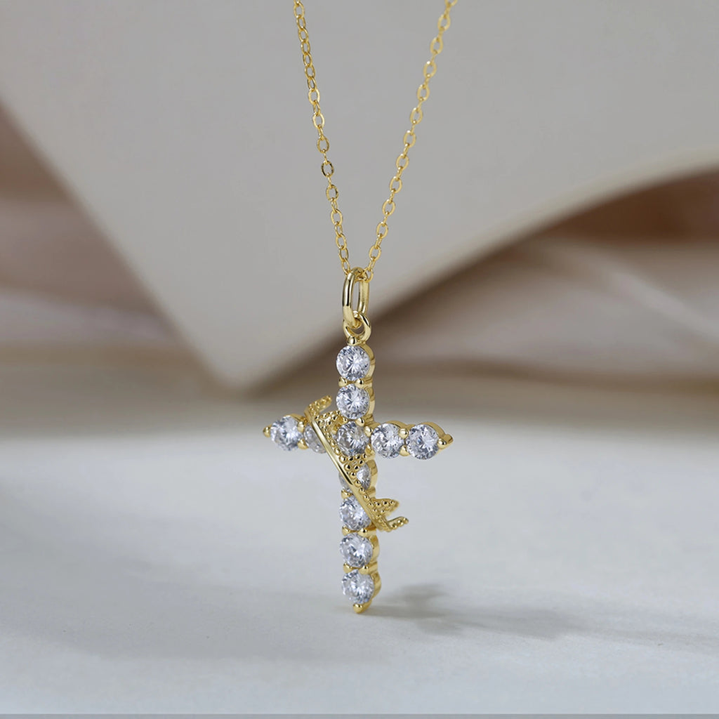 Gold-tone cross pendant with clear cubic zirconia stones and a diagonal thorn-textured band