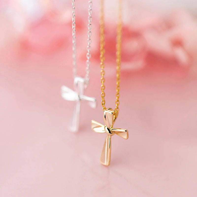 Gold-tone flared-arm cross necklace in focus with a silver-tone cross necklace in the background