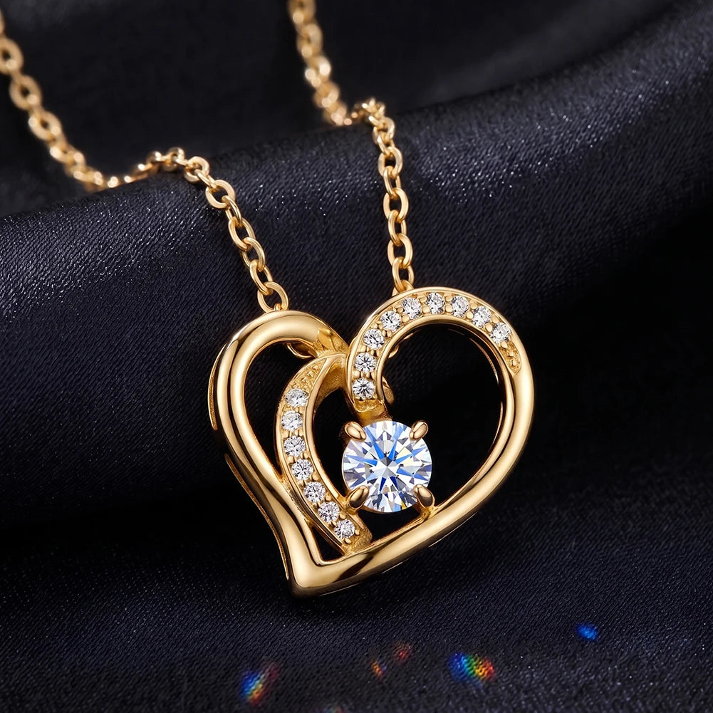 Gold-tone overlapping heart pendant on dark blue fabric with a stone-lined inner curve