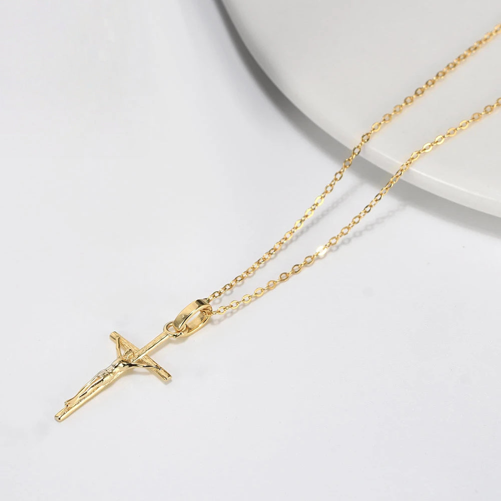 Gold-tone crucifix pendant resting beside a white dish, showing the oval-link chain and wide bail