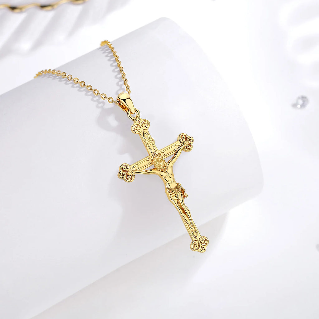 Gold-plated sterling silver crucifix pendant on a chain, displayed on a white curved surface