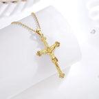 Gold-plated sterling silver crucifix pendant on a chain, displayed on a white curved surface