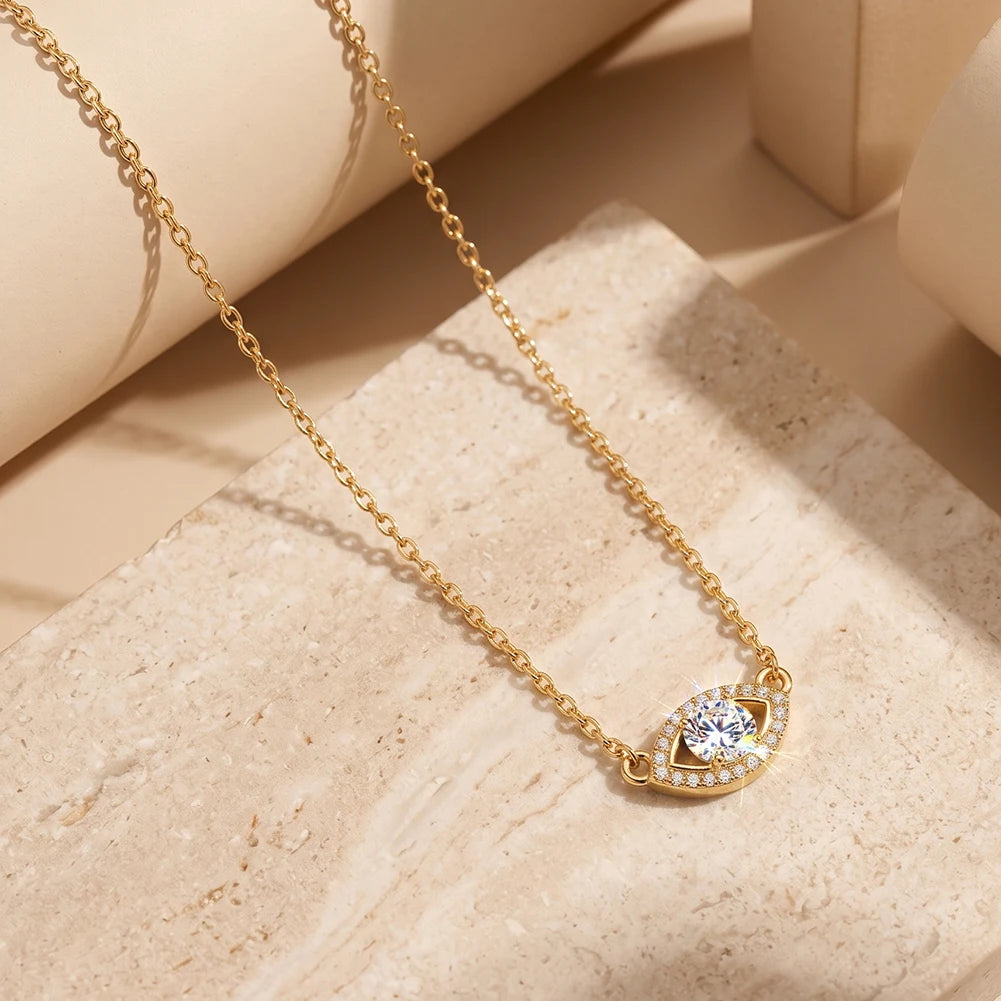 Gold-tone evil eye necklace arranged on a pale stone surface with oval-link chain