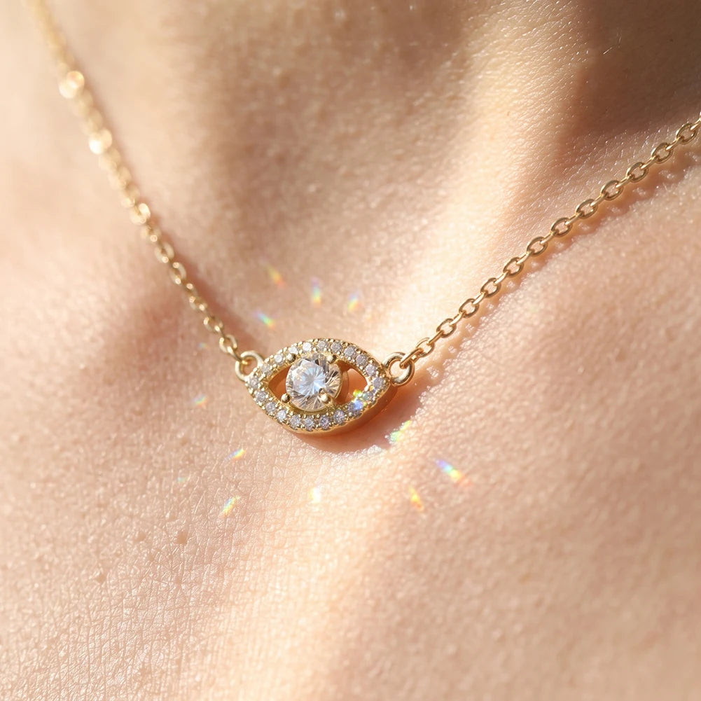 Gold-tone evil eye necklace worn at the collarbone with sparkling center moissanite